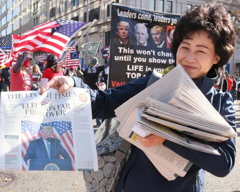 Woman holding copy of The Epoch Times CFO